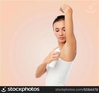 beauty, hygiene and people concept - beautiful young woman applying antiperspirant or spray deodorant over beige background. woman with antiperspirant deodorant over white. woman with antiperspirant deodorant over white