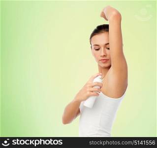 beauty, hygiene and people concept - beautiful young woman applying antiperspirant or spray deodorant over green natural background. woman with antiperspirant deodorant over white