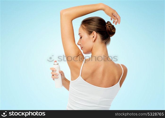 beauty, hygiene, bodycare and people concept - beautiful young woman applying antiperspirant or spray deodorant over blue background. woman with antiperspirant deodorant over white