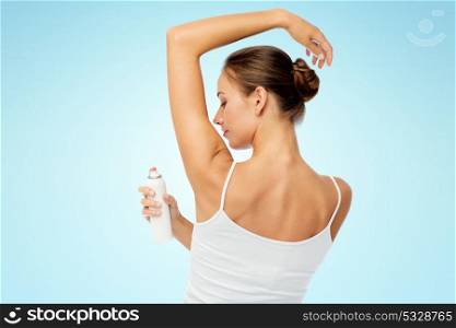 beauty, hygiene, bodycare and people concept - beautiful young woman applying antiperspirant or spray deodorant over blue background. woman with antiperspirant deodorant over white