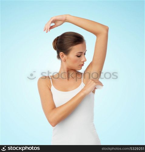 beauty, hygiene, bodycare and people concept - beautiful young woman applying antiperspirant or stick deodorant over blue background. woman with antiperspirant deodorant over white