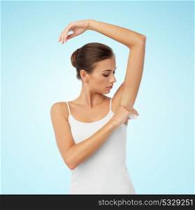 beauty, hygiene, bodycare and people concept - beautiful young woman applying antiperspirant or stick deodorant over blue background. woman with antiperspirant deodorant over white