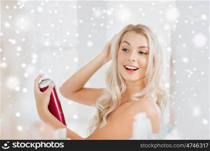 beauty, hygiene, hairstyle, morning and people concept - smiling young woman with hairspray styling her hair and looking to mirror at home bathroom over snow