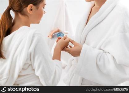 beauty, hygiene, morning and people concept - close up of mother and daughter applying lotion to cotton pad at bathroom. mother and daughter applying lotion to cotton pad