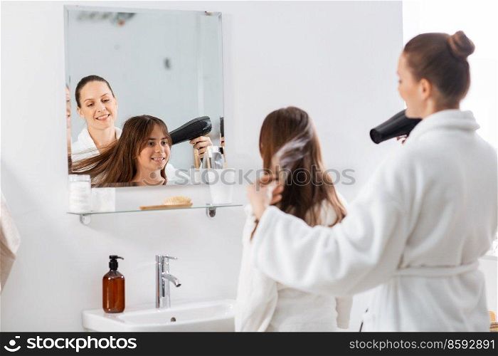 beauty, hygiene, morning and people concept - happy smiling mother and daughter with hair dryer at bathroom. mother and daughter drying hair at bathroom