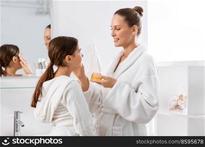 beauty, hygiene, morning and people concept - happy smiling mother and daughter with moisturizer at bathroom. mother and daughter with moisturizer at bathroom