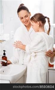 beauty, hygiene, morning and people concept - happy smiling mother and little daughter with liquid soap in bathroom. mother and daughter with liquid soap in bathroom