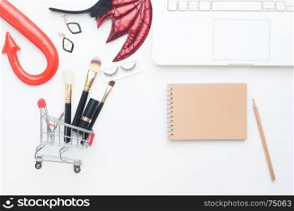Beauty items in shopping cart with Halloween costume, Laptop computer and notebook with copy space, Online shopping and Halloween concept
