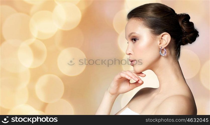 beauty, jewelry, accessories, people and luxury concept - beautiful asian woman with earring over holidays lights background