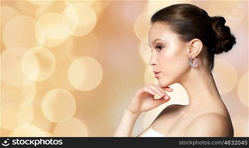 beauty, jewelry, accessories, people and luxury concept - beautiful asian woman with earring over holidays lights background