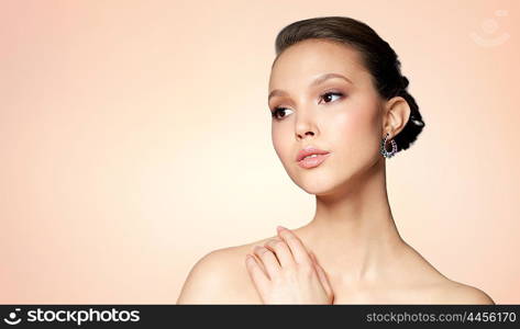 beauty, jewelry, accessories, people and luxury concept - close up of beautiful asian woman face with earring over beige background