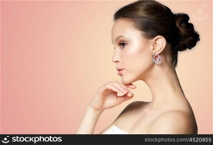beauty, jewelry, accessories, people and luxury concept - close up of beautiful asian woman face with earring over beige background