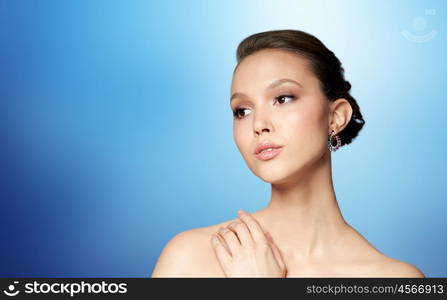 beauty, jewelry, accessories, people and luxury concept - close up of beautiful asian woman face with earring over blue background