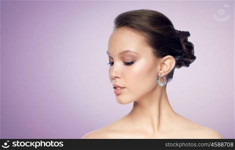 beauty, jewelry, accessories, people and luxury concept - close up of beautiful asian woman face with earring over violet background
