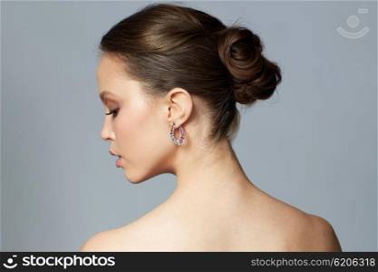 beauty, jewelry, accessories, people and luxury concept - close up of beautiful asian woman face with earring over gray background