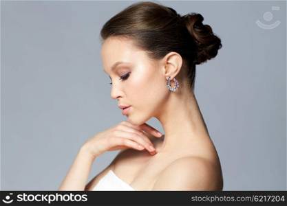 beauty, jewelry, accessories, people and luxury concept - close up of beautiful asian woman face with earring over gray background