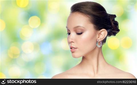 beauty, jewelry, accessories, people and luxury concept - close up of beautiful asian woman face with earring over summer green lights background