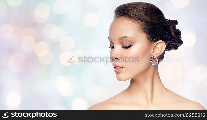 beauty, jewelry, accessories, people and luxury concept - close up of beautiful asian woman face with earring over blue holidays lights background