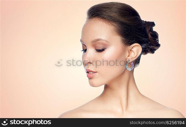 beauty, jewelry, accessories, people and luxury concept - close up of beautiful asian woman face with earring over beige background