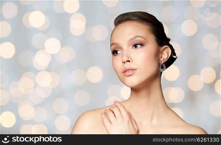 beauty, jewelry, accessories, people and luxury concept - close up of beautiful asian woman face with earring over holidays lights background