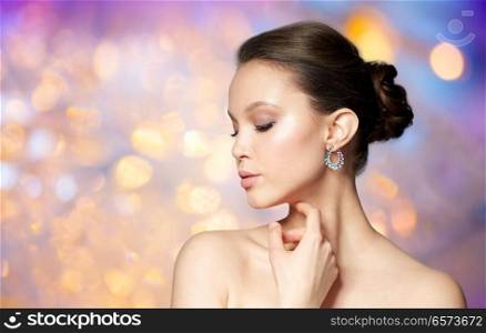 beauty, jewelry, accessories, people and luxury concept - close up of beautiful asian woman face with earring over holidays lights background. close up of beautiful woman face with earring