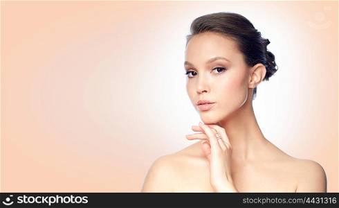 beauty, jewelry, accessories, people and luxury concept - face of beautiful young asian woman with golden ring over beige background