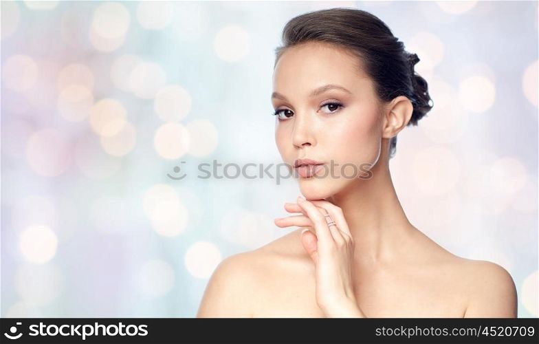 beauty, jewelry, accessories, people and luxury concept - face of beautiful young asian woman with golden ring over holidays lights background