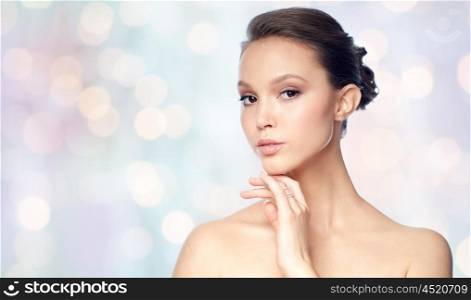 beauty, jewelry, accessories, people and luxury concept - face of beautiful young asian woman with golden ring over holidays lights background