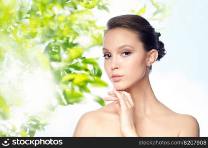 beauty, jewelry, accessories, people and luxury concept - face of beautiful young asian woman with golden ring over green natural background