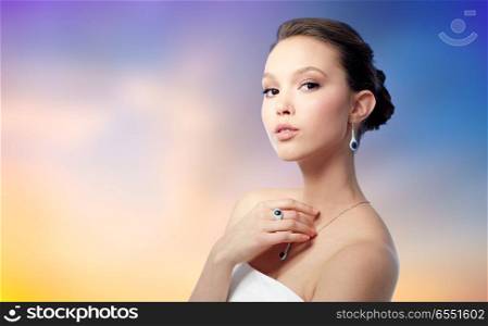 beauty, jewelry and luxury concept - beautiful asian woman or bride with earring, finger ring and pendant over pastel background. beautiful woman with earring, ring and pendant. beautiful woman with earring, ring and pendant