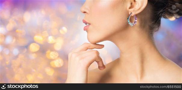 beauty, jewelry and luxury concept - close up of beautiful woman face with earring over holidays lights background. close up of beautiful woman face with earring. close up of beautiful woman face with earring