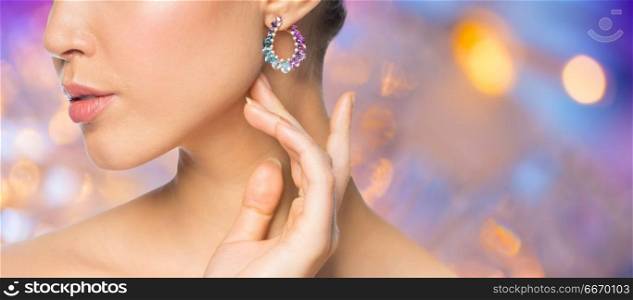 beauty, jewelry and luxury concept - close up of beautiful woman face with earring over holidays lights background. close up of beautiful woman face with earring. close up of beautiful woman face with earring