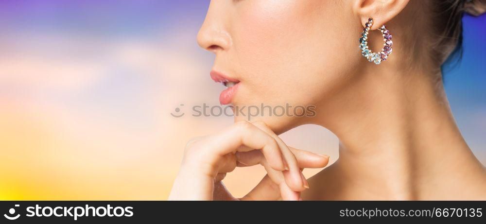 beauty, jewelry and luxury concept - close up of beautiful woman face with earring over pastel background. close up of beautiful woman face with earring. close up of beautiful woman face with earring