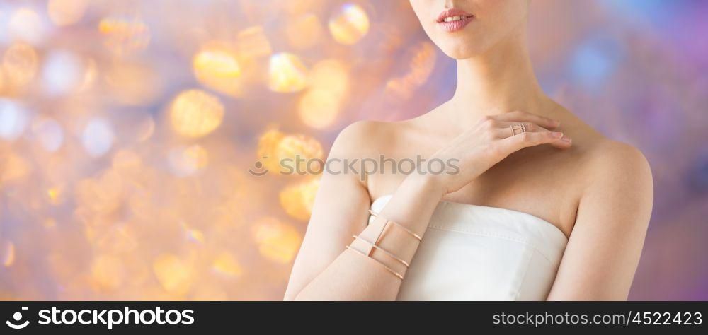 beauty, jewelry and luxury concept - close up of beautiful woman with golden ring and bracelet over holidays lights background. close up of beautiful woman with ring and bracelet. close up of beautiful woman with ring and bracelet