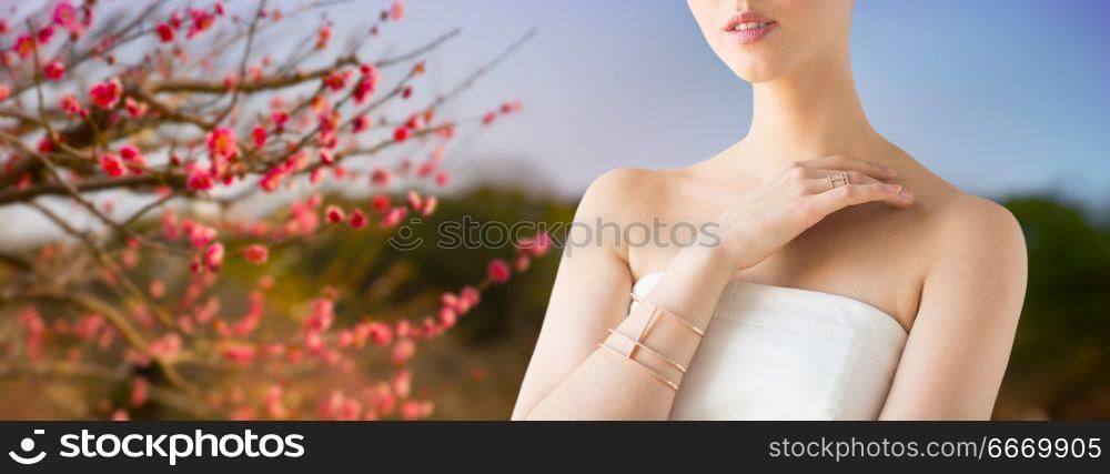 beauty, jewelry and luxury concept - close up of beautiful woman with golden ring and bracelet over natural spring cherry blossom background. close up of beautiful woman with ring and bracelet. close up of beautiful woman with ring and bracelet