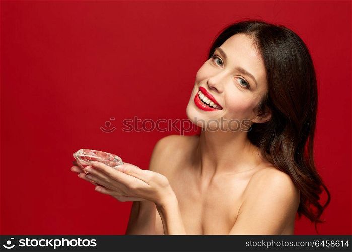 beauty, jewelry and people concept - happy smiling young woman with red lipstick holding big diamond. beautiful woman with red lipstick holding diamond