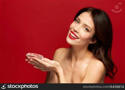 beauty, jewelry and people concept - happy smiling young woman with red lipstick holding big diamond. beautiful woman with red lipstick holding diamond