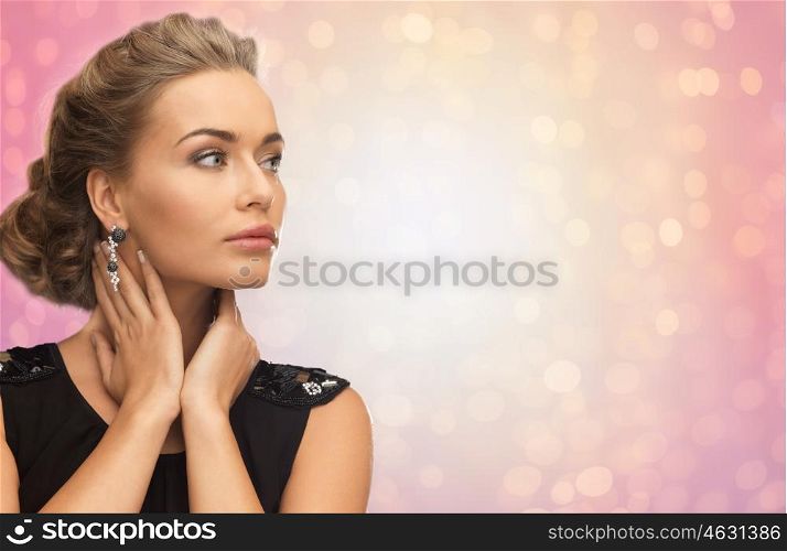 beauty, jewelry, holidays and people concept - beautiful woman in evening dress wearing diamond earrings over rose quartz and serenity lights background