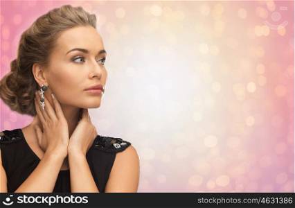 beauty, jewelry, holidays and people concept - beautiful woman in evening dress wearing diamond earrings over rose quartz and serenity lights background