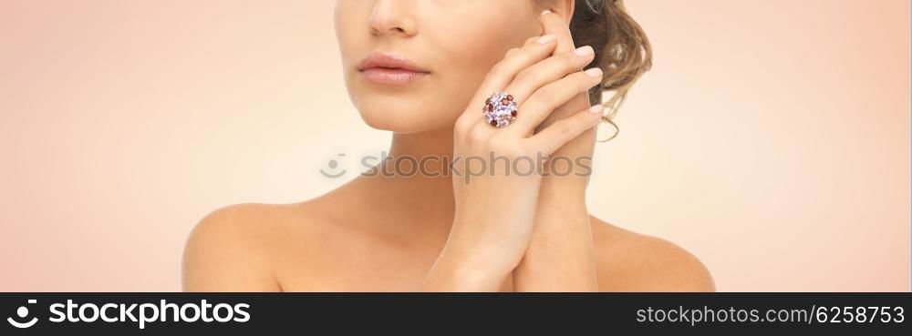 beauty, jewelry, people and accessories concept - close up of woman with cocktail ring on hand over beige background