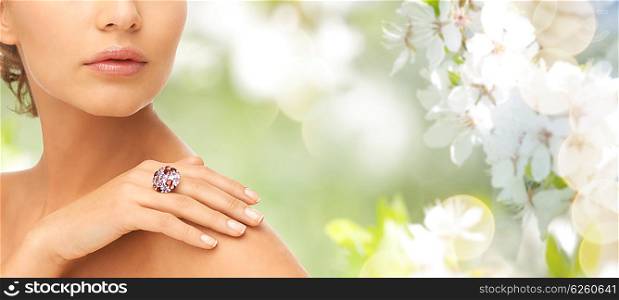 beauty, jewelry, people and accessories concept - close up of woman with cocktail ring on hand over summer garden and cherry blossom background