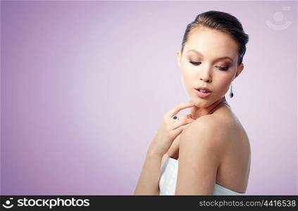 beauty, jewelry, people and luxury concept - beautiful asian woman or bride with earring and finger ring over violet background