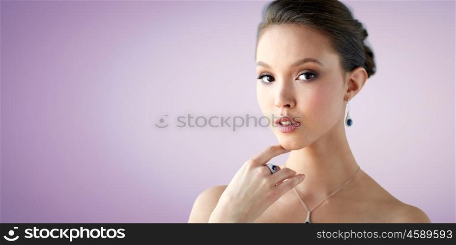 beauty, jewelry, people and luxury concept - beautiful asian woman or bride with earring, finger ring and pendant over violet background