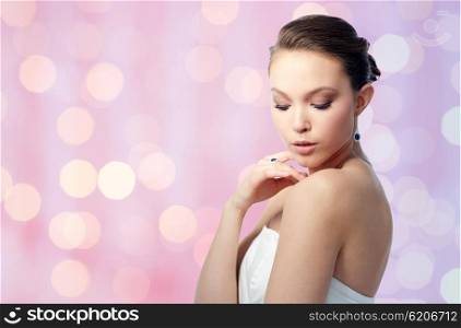 beauty, jewelry, people and luxury concept - beautiful asian woman or bride with earring and finger ring over holidays lights background