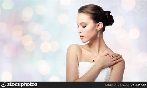 beauty, jewelry, people and luxury concept - beautiful asian woman or bride with earring, finger ring and pendant over holidays lights background