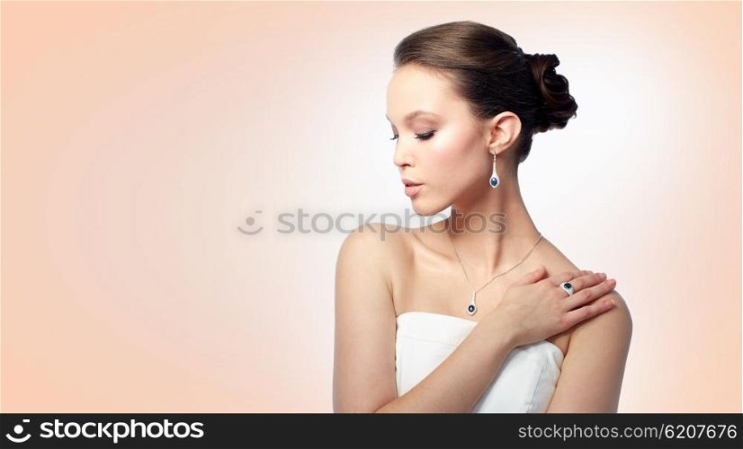 beauty, jewelry, people and luxury concept - beautiful asian woman or bride with earring, finger ring and pendant over beige background