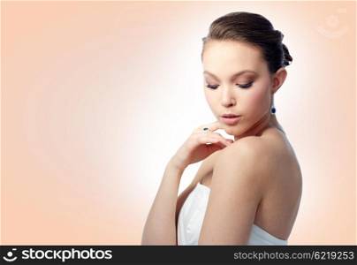 beauty, jewelry, people and luxury concept - beautiful asian woman or bride with earring and finger ring over beige background