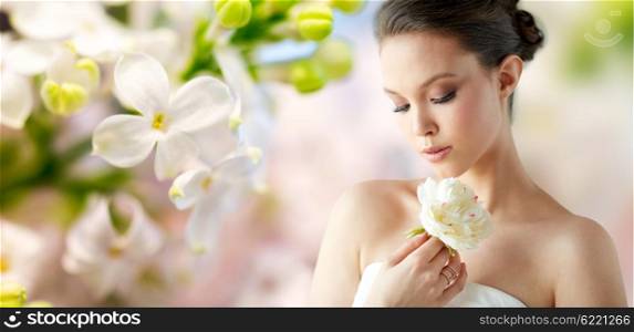 beauty, jewelry, people and luxury concept - beautiful asian woman or bride in white dress with peony flower and golden ring over natural spring lilac blossom background