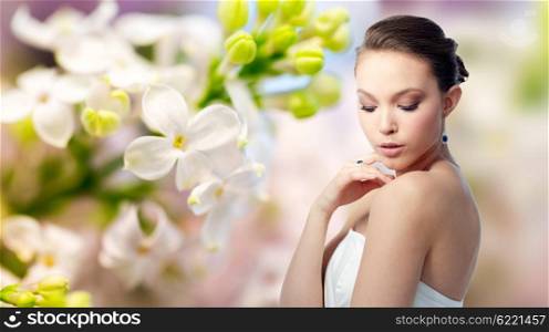 beauty, jewelry, people and luxury concept - beautiful asian woman or bride with earring and finger ring over natural spring lilac blossom background