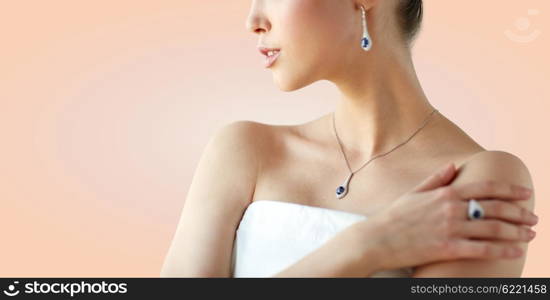 beauty, jewelry, people and luxury concept - beautiful asian woman or bride with earring, finger ring and pendant over beige background